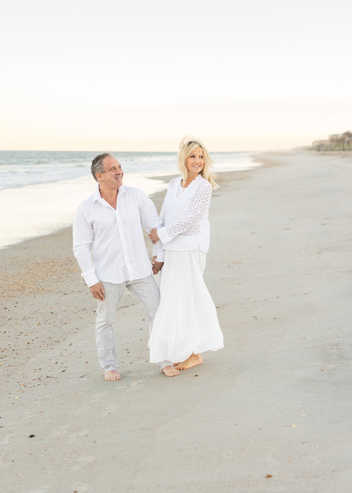 Steve and Lori Gordon walking on the beach at sunset